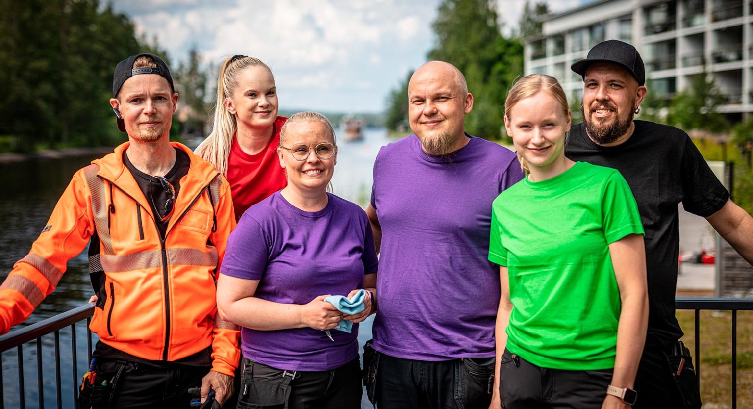 Iloiset kiinteistöalan työntekijät poseeravat kameralle ulkona